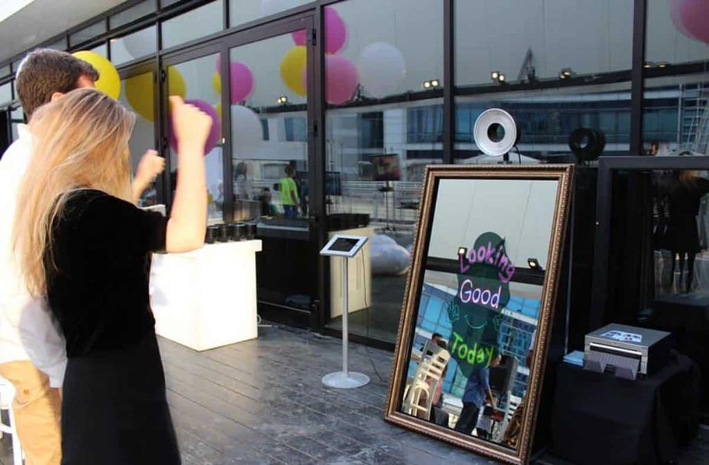 Guests using a mirror photo booth with 'Looking Good Today' message