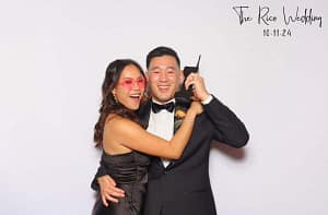 a couple posing for a photo in a wedding photo booth while holding a retro brick phone