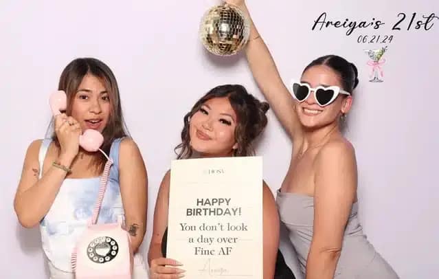Three ladies posing in a photo booth for Areiya’s 21st birthday, with the celebrant in the middle.