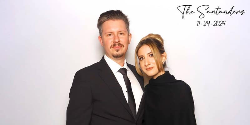A stylish couple posing at a photo booth rental in Burbank, dressed in formal black attire.