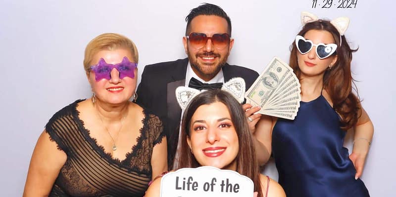 A group posing with fun props at The Santander's event photo booth rental in Carlsbad, smiling and playful.