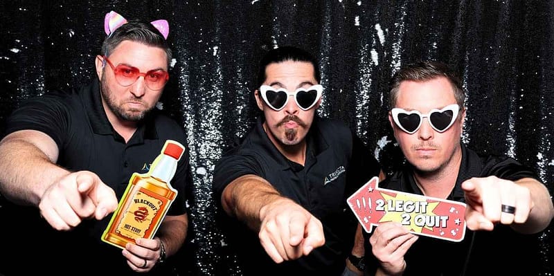Three colleagues posing with fun props at the Trifecta Painting & Construction photo booth rental in Long Beach.