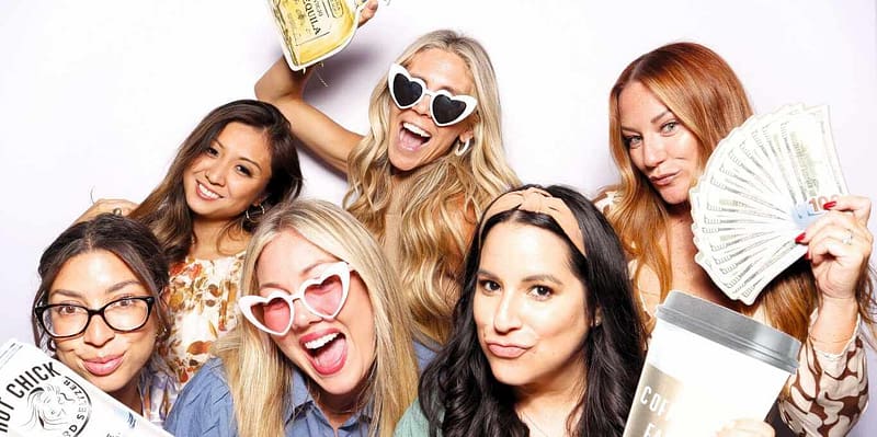 Smiling ladies with fun props at an office event with photo booth rental in San Diego.