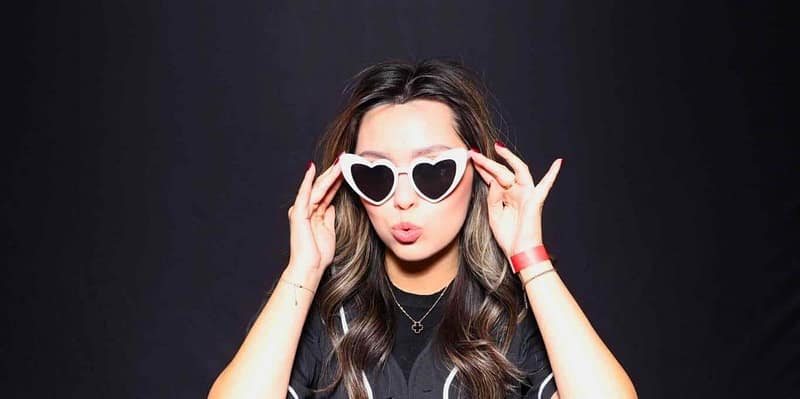 A woman posing with heart-shaped glasses at the Service Titan photo booth rental in Santa Ana, puckering lips.