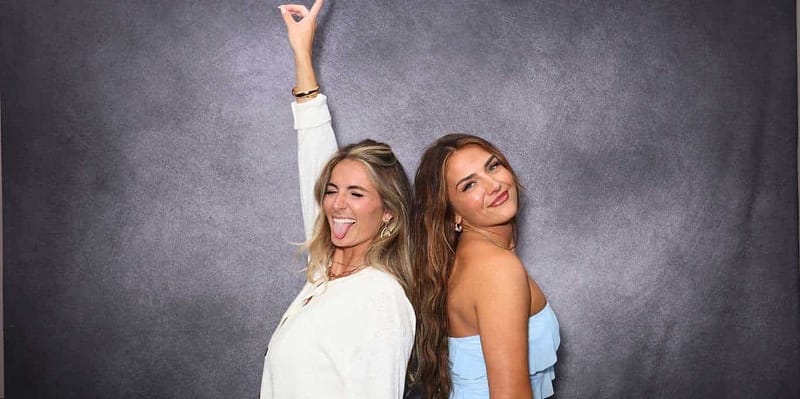 Two ladies pose playfully at a photo booth during a Hollywood salon celebration event.