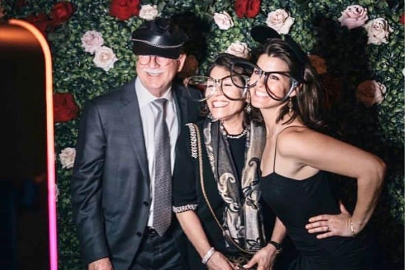 Guests enjoying a wedding photo booth with rose backdrop.