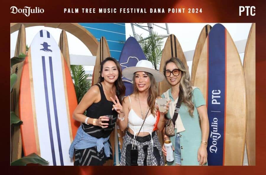 Three women posing with surfboard backdrop at Don Julio Palm Tree Music Festival Dana Point 2024